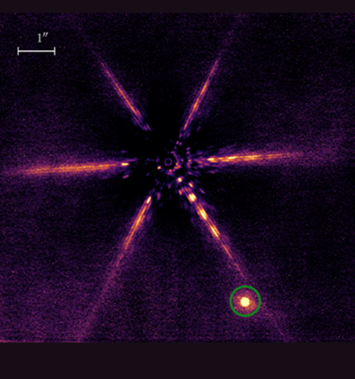 This is an image of exoplanet KOINTREAU-1 b. The image contains a faint circle in the center from which six orange-yellow arms extend; the planet appears as a bright orange orb in the lower-left corner next to one of the arms.